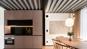 Une cuisine moderne dotée d’appareils électroménagers intégrés, un coin repas avec une table et des chaises en bois, et un luminaire suspendu.