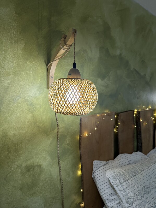 Ein Zimmer mit einem hölzernen Kopfteil, einer gewebten Lampe und Lichterketten.
