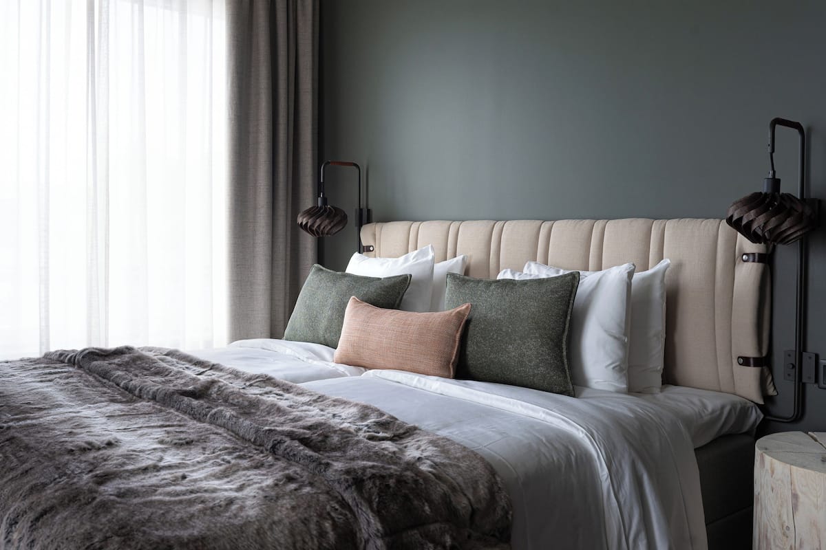 A bedroom with a tufted headboard, a fluffy throw blanket, and multiple pillows.