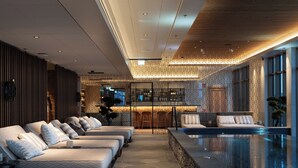 Un área de spa moderna con piscina, sillas de descanso y un bar.