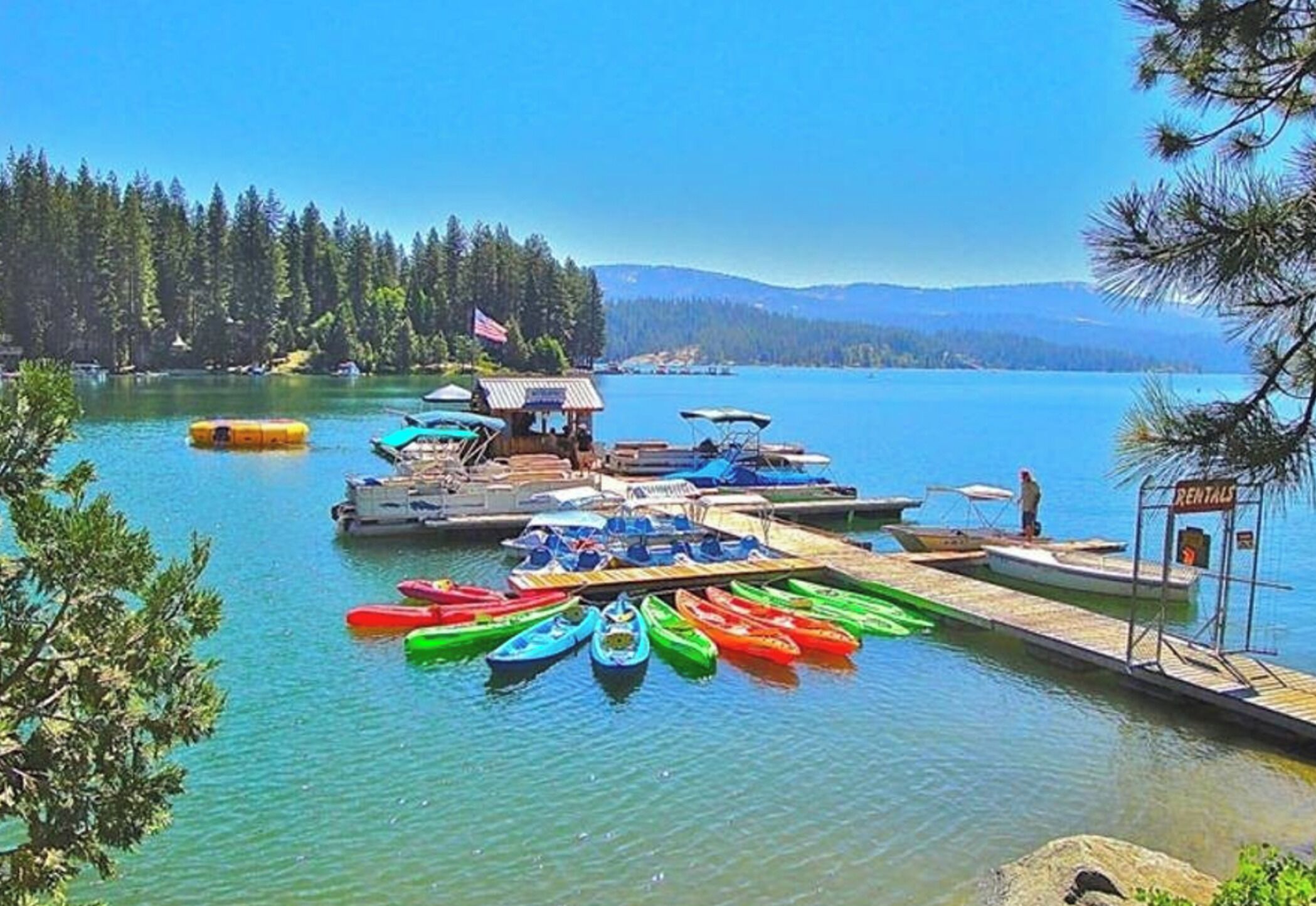 Un quai au bord du lac, avec des canoës et une pancarte indiquant la location de bateaux.