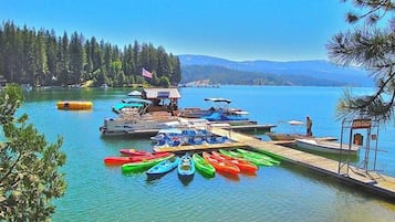 Un quai au bord du lac, avec des canoës et une pancarte indiquant la location de bateaux.
