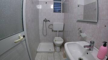 A small bathroom with a shower, toilet, and sink.
