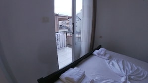 A hotel room with a bed, two white towels, a window, and a view of the outside balcony. - Casa Mia Hostel SR (Sarandë)
