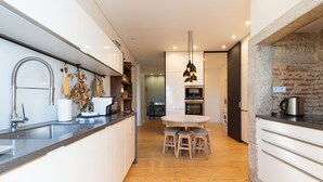 A modern kitchen with a central island, stainless steel appliances, and a hanging light fixture. - Charming Graça Apartment, Lisbon City Centre, TTL354a (Lisboa ciudad)