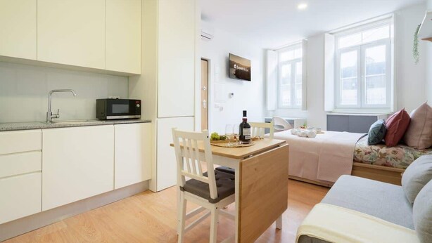 Een ruimtelijke woonkamer met een kitchenette, een eethoek en een bank.