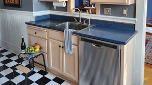 A kitchen with wooden cabinets, a stainless steel dishwasher, and a checkered floor. - Historic Craftsman 3 Bedroom Home in Uptown Butte (Butte)