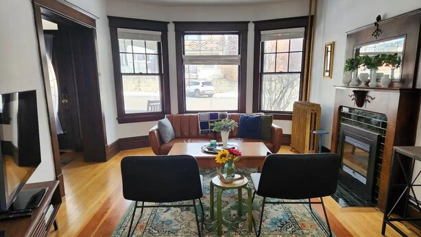 A cozy dining area with a wooden table, two chairs, a patterned rug, and a sofa with cushions. - Historic Craftsman 3 Bedroom Home in Uptown Butte (Butte)