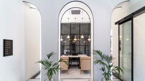 Een receptiegedeelte met een balie, twee planten in potten en een bordje met aanwijzingen naar de receptie, het restaurant en het toilet.
