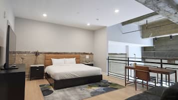 Une chambre moderne comprenant un lit, des tables de chevet, un bureau et un balcon avec une rambarde.