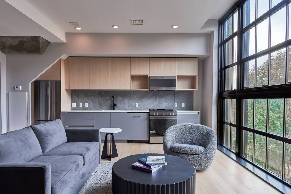 A modern kitchen with a built-in oven, microwave, and large windows.