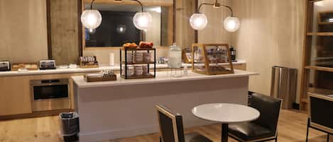 Una cocina moderna con una isla central, armarios de madera y una zona de comedor con dos sillas y una mesa.