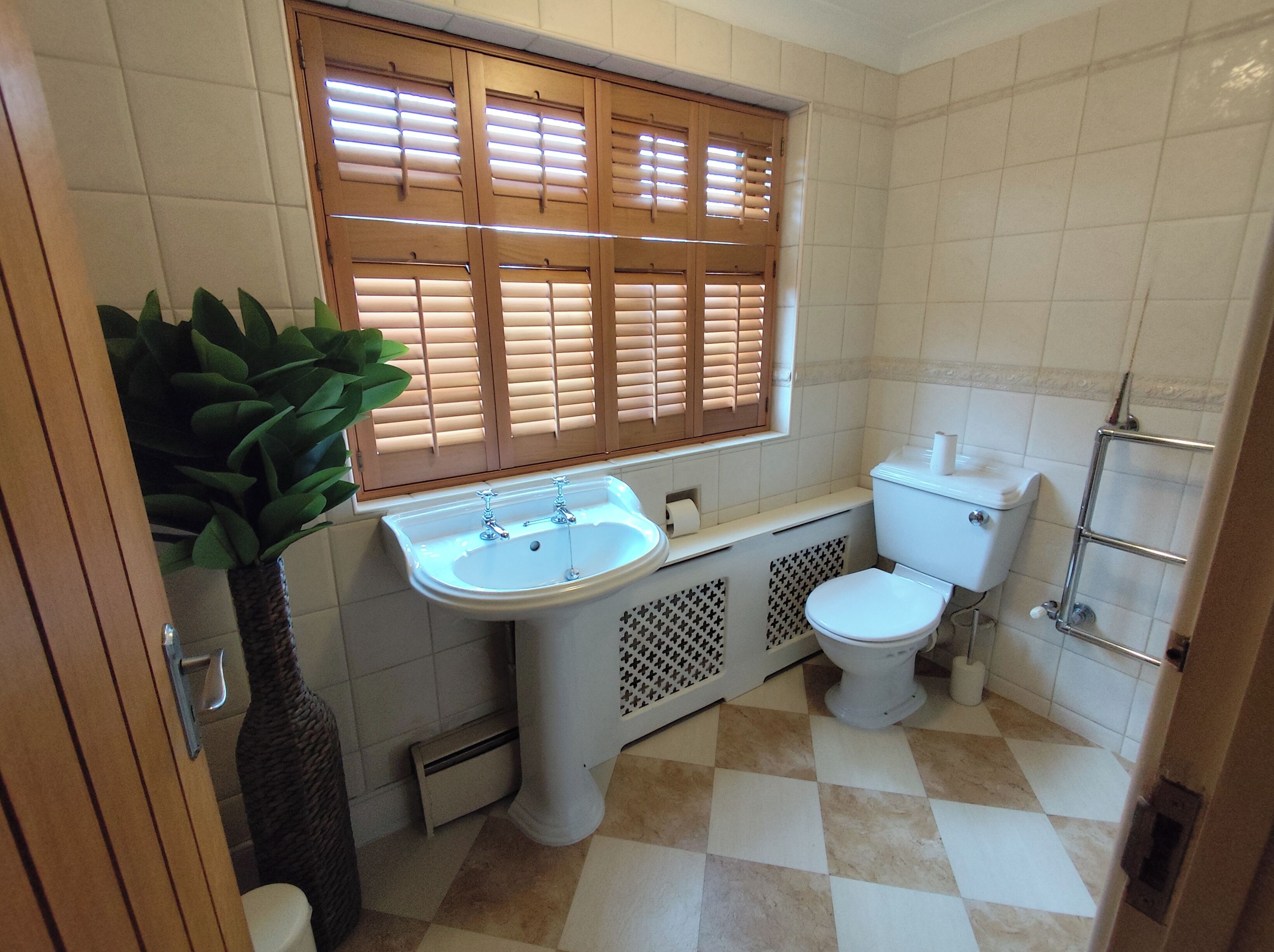 A bathroom with a sink, toilet, and window with blinds.