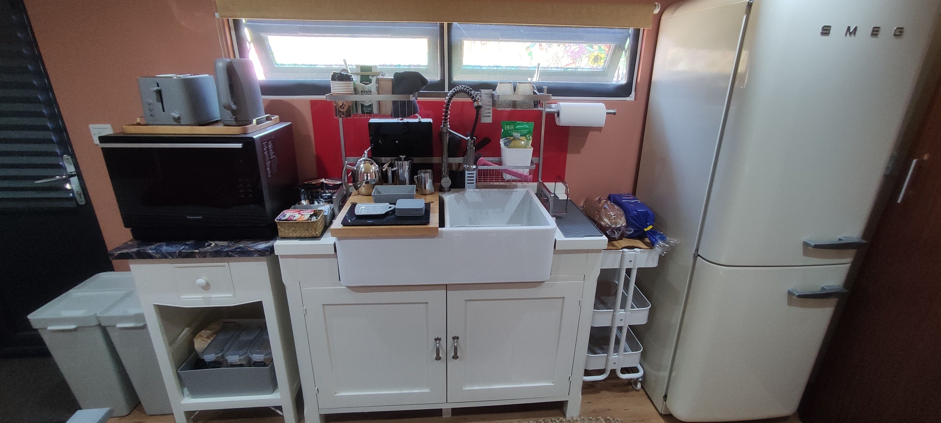 Een kleine keuken met een spoelbak, aanrecht en een koelkast.