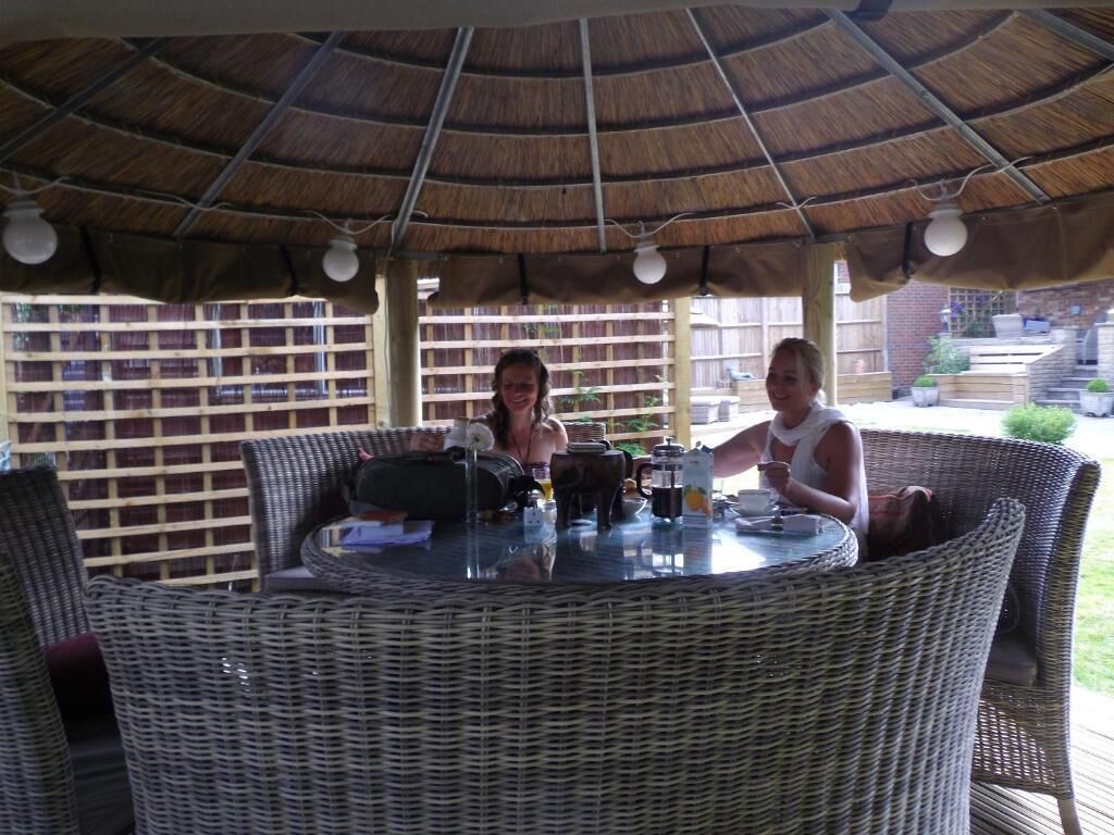 An outdoor dining area with wicker furniture and a thatched roof.