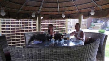 An outdoor dining area with wicker furniture and a thatched roof.