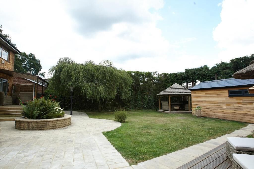 Ein Garten mit einem Kiesweg, einem hölzernen Pavillon und einer Rasenfläche.