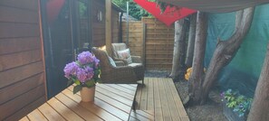 Une terrasse en bois avec des meubles en osier et une plante en pot.