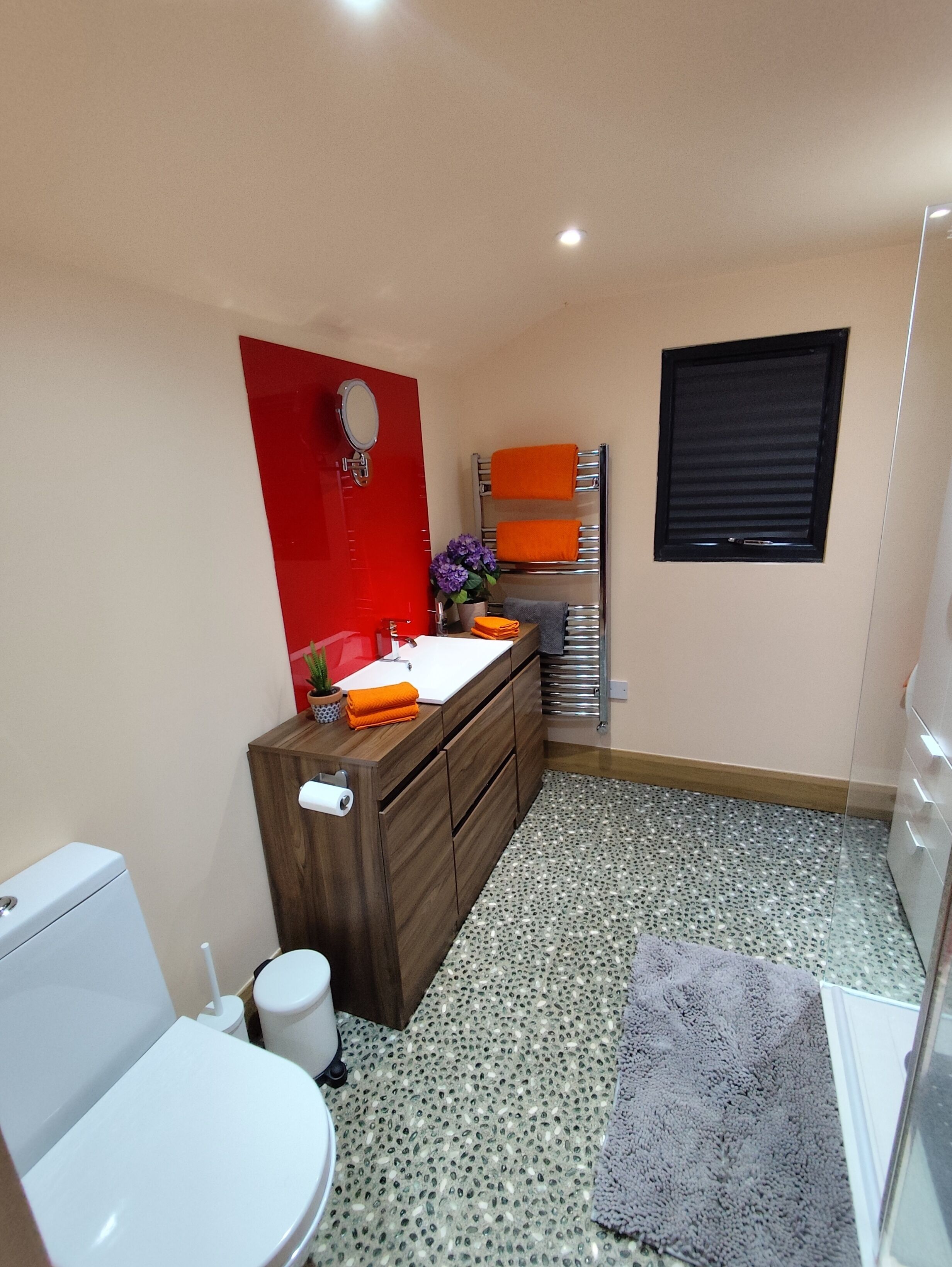 Un baño pequeño con inodoro blanco, tocador de madera con espejo y un lavamanos.