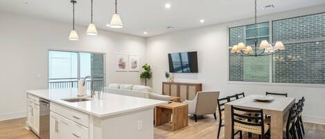 Une cuisine moderne dotée d’un îlot central, de meubles blancs et de luminaires suspendus.