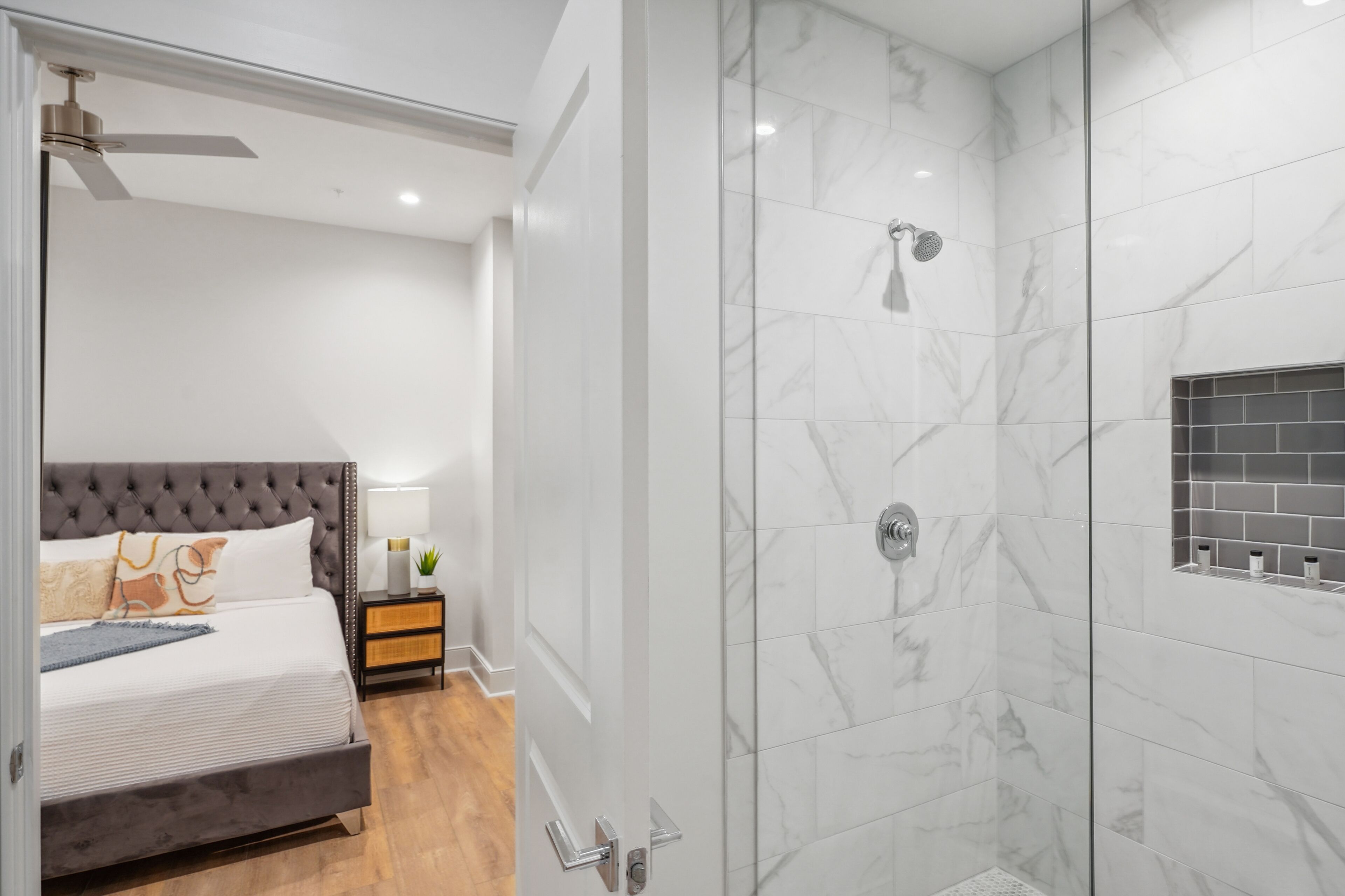 Un dormitorio moderno con una cama grande, una mesita de noche y un baño con cabina de ducha de vidrio.
