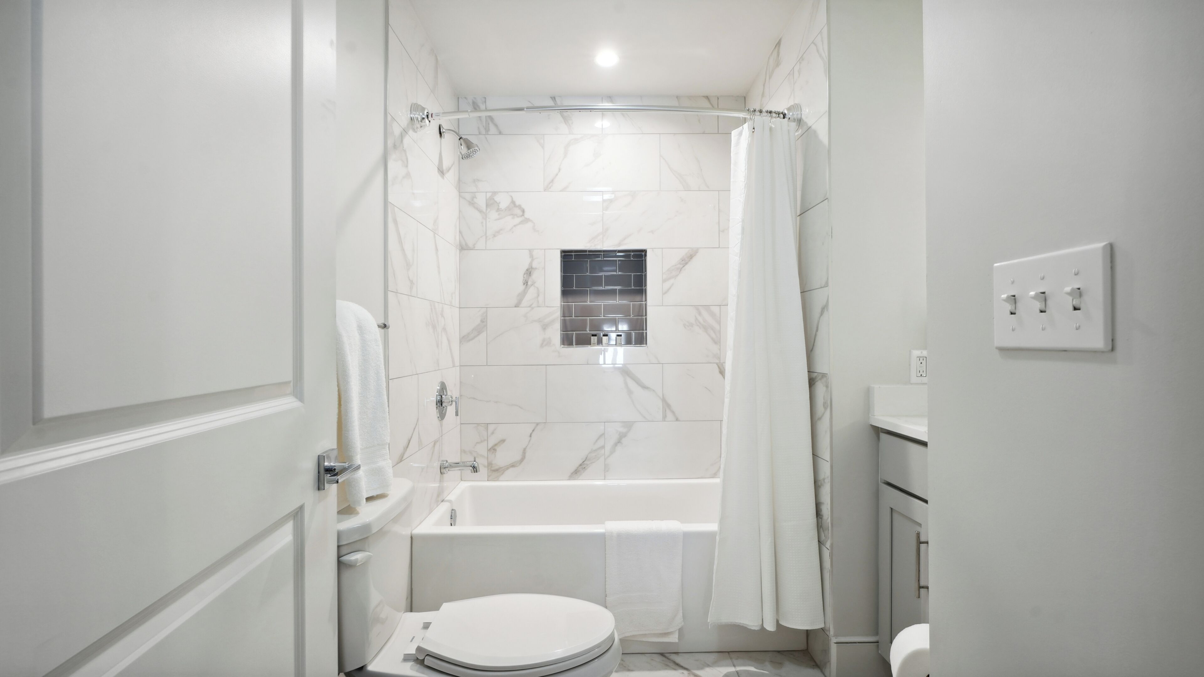 Un baño moderno con bañera, inodoro y zona de ducha.