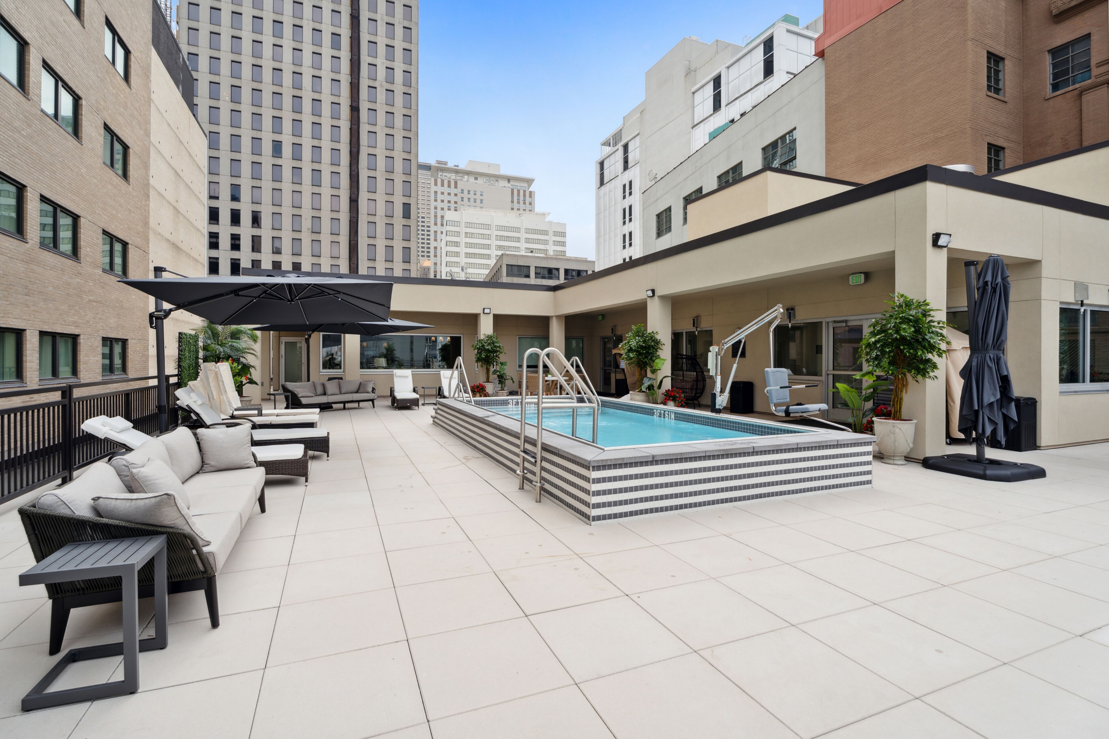 A rooftop pool area with lounge chairs, a pool, and a staircase leading to an upper level.