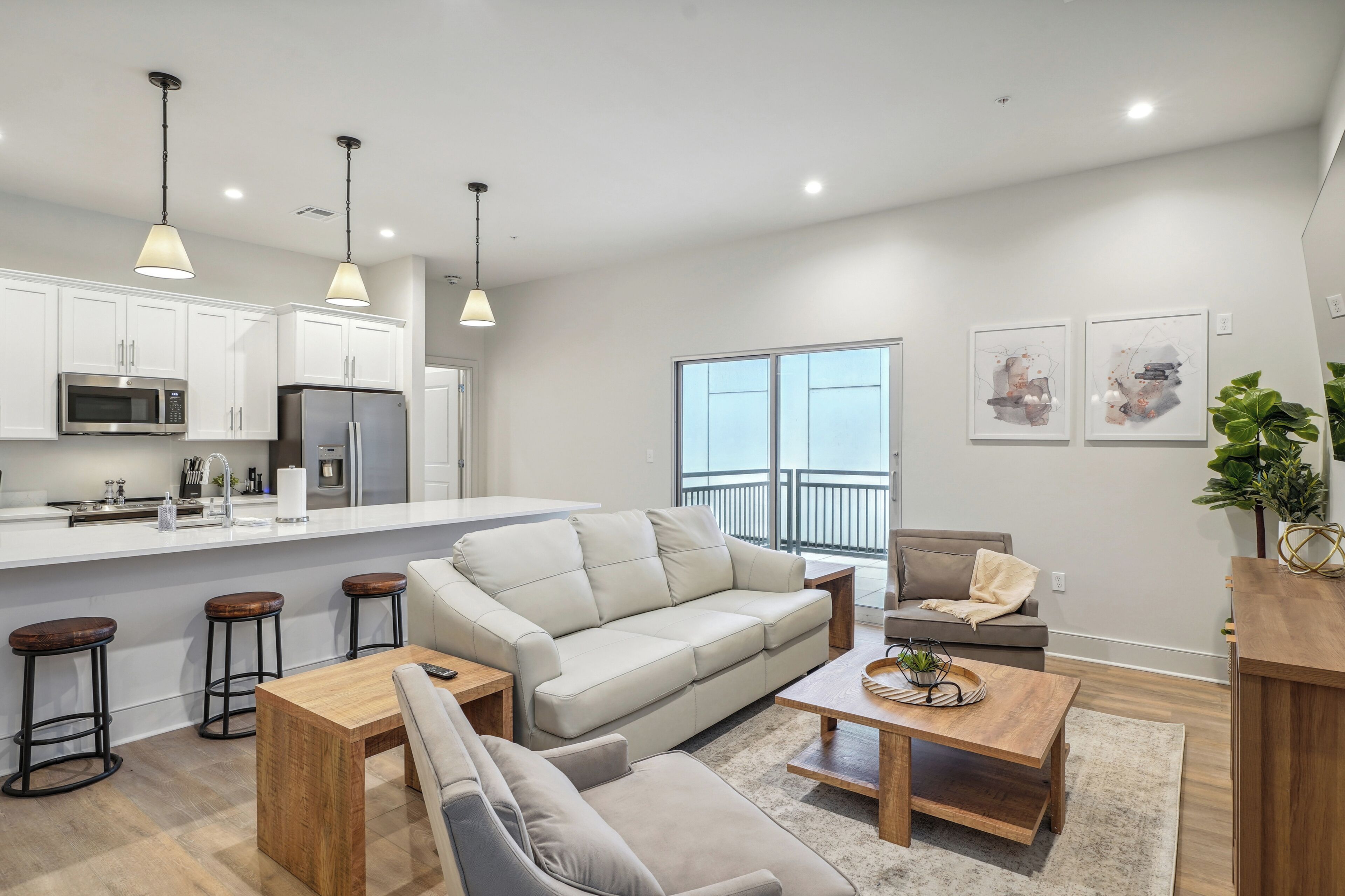 A modern kitchen with white cabinets, stainless steel appliances, and pendant lighting.