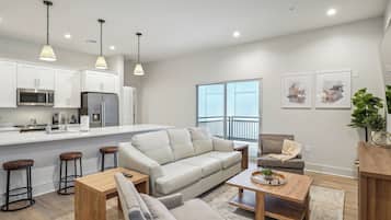 A modern kitchen with white cabinets, stainless steel appliances, and pendant lighting.