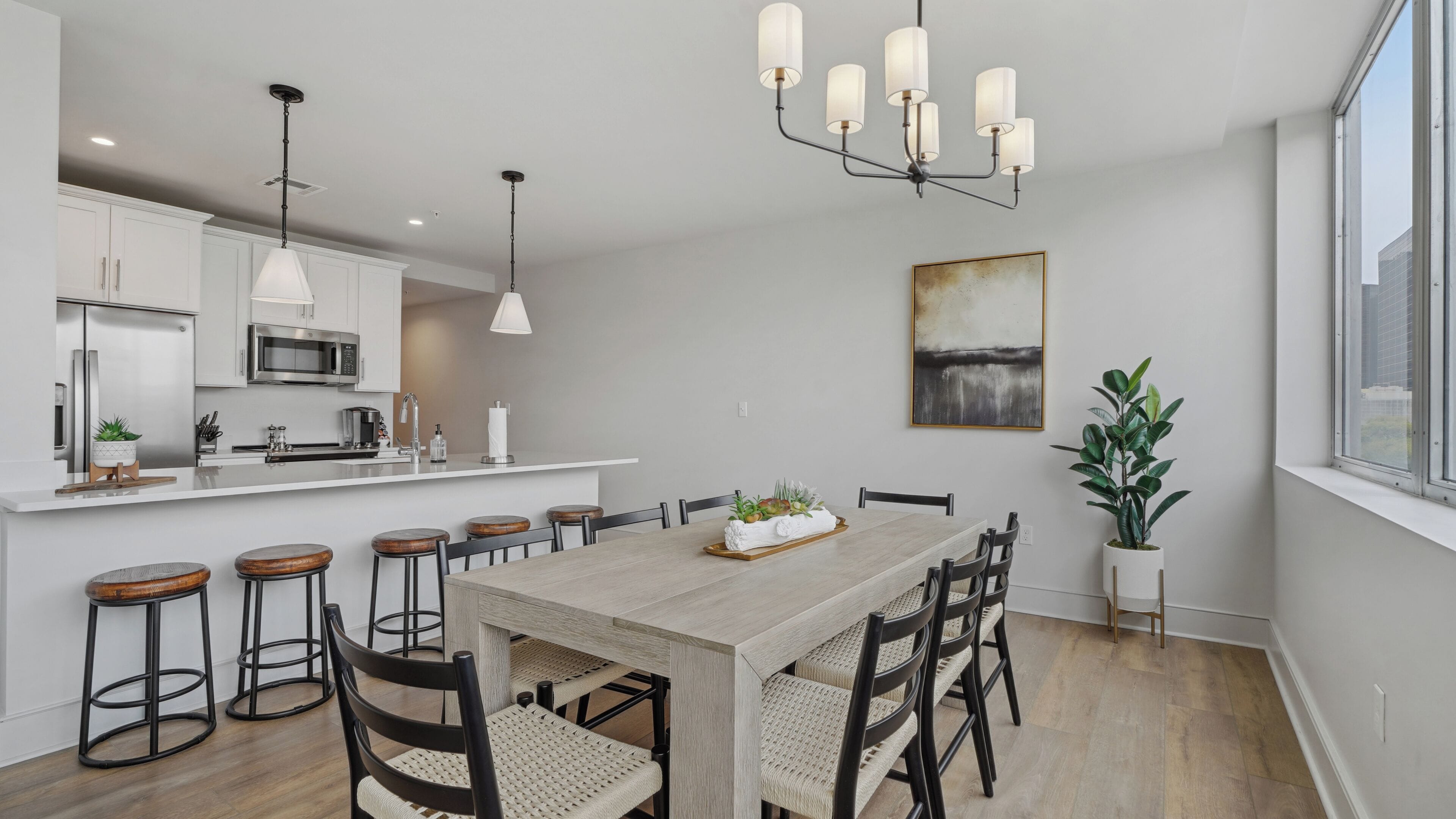 Una cocina moderna con armarios blancos, electrodomésticos de acero inoxidable y una isla central con taburetes.