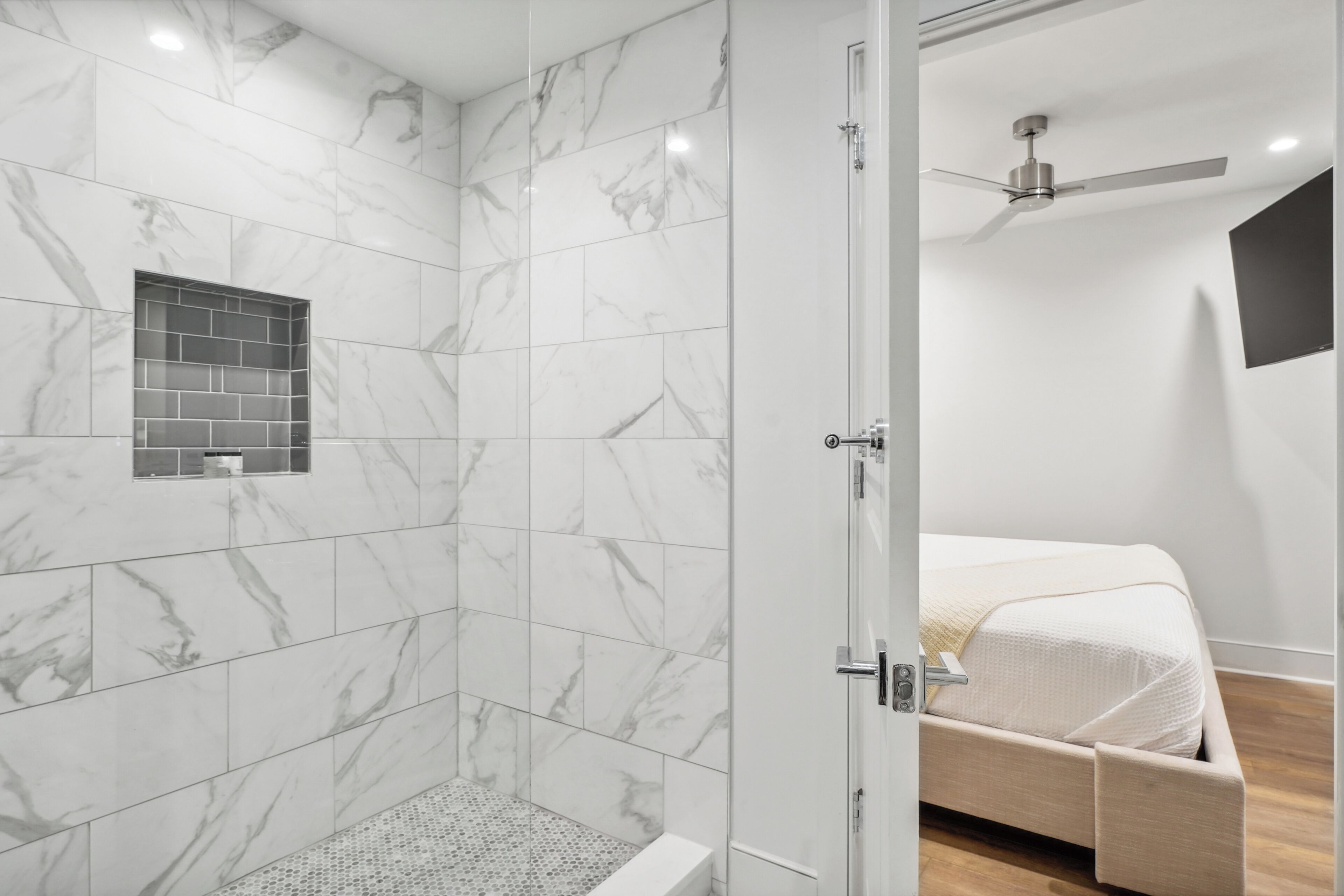 A modern bathroom with a shower, a toilet, and a bed with a wooden headboard.