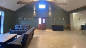 A spacious living area with a high ceiling, a large window, and a fireplace.