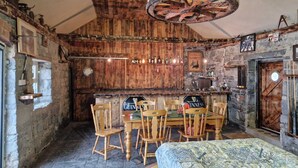 A rustic bar area with wooden furniture, a stone wall, and a Guinness sign.