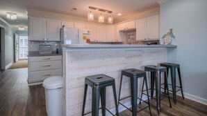 A kitchen with white cabinets, a wooden island, and bar stools.