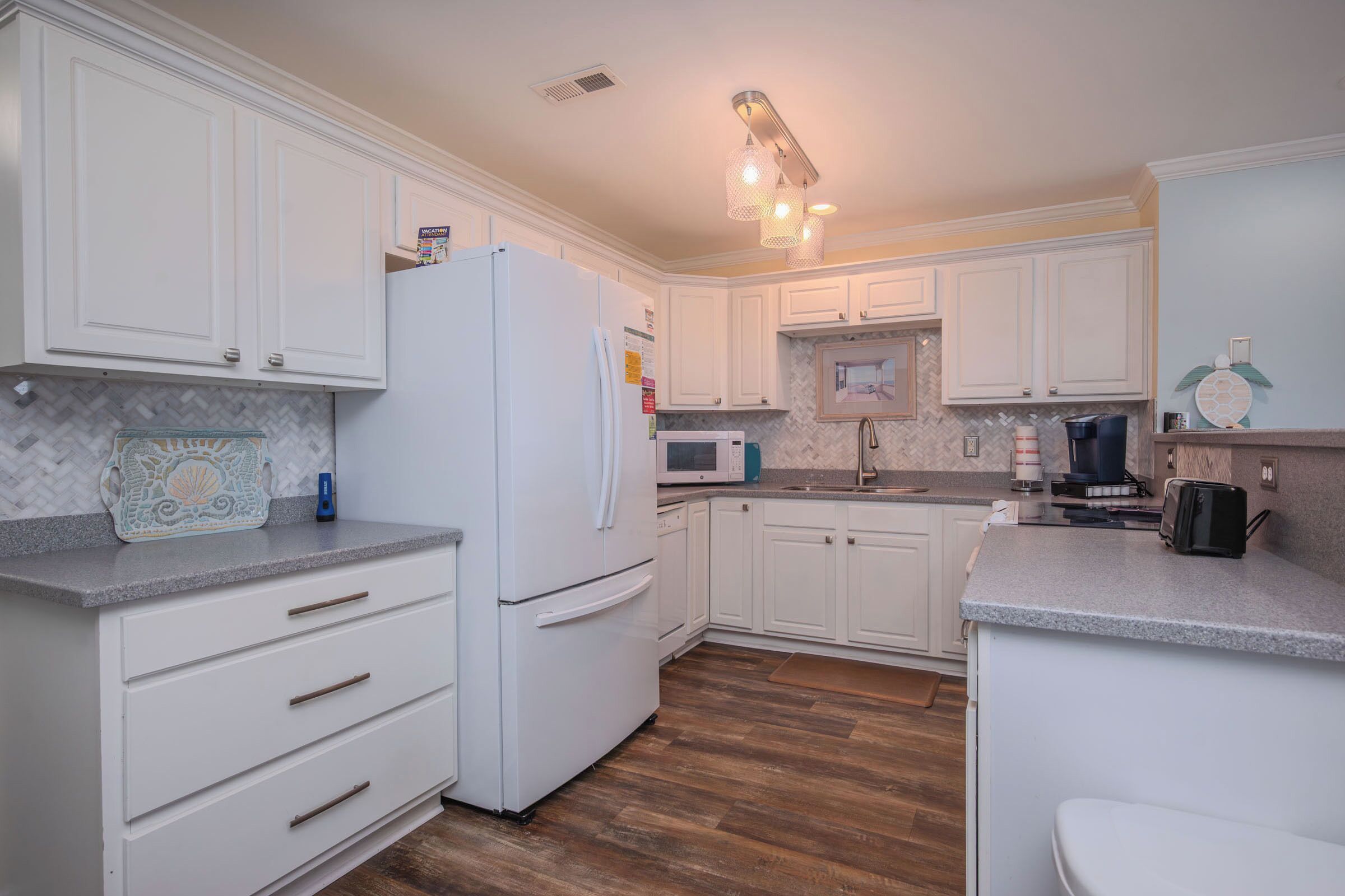 A modern kitchen with white cabinetry, a built-in microwave, and a stainless steel refrigerator.