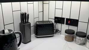 A modern kitchen with a black coffee maker, toaster, and jars on the counter. - Impeccable 3-bed House in Walsall (Walsall)