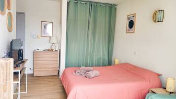 Une chambre à coucher avec un lit, un bureau avec un ordinateur, une commode et une lampe.