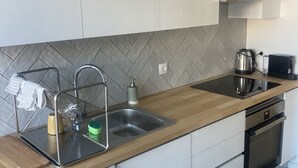Eine moderne Küche mit weißen Schränken, einer Edelstahl-Spüle, einem eingebauten Geschirrspüler und einer Rückwand mit Fischgrätenmuster.