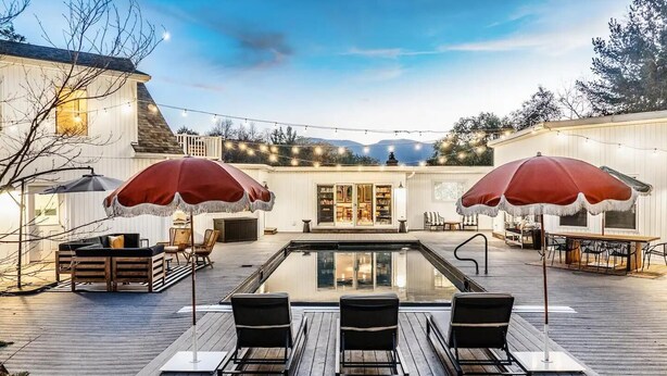 A poolside area with a wooden deck, two red umbrellas, and outdoor seating. - Heated Pool, Hot Tub & Mountain Views on 15 Acres! New Listing Special! (Freehold)