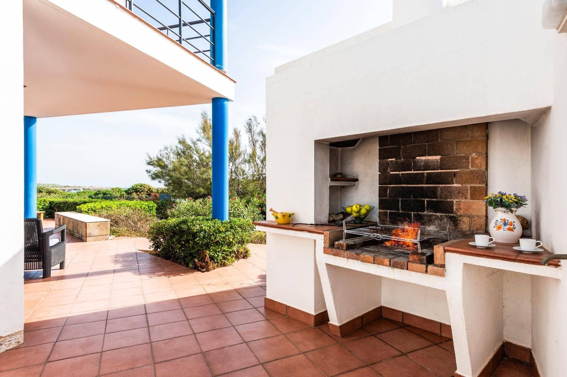 A patio with a grill, outdoor seating, and a view of the countryside.