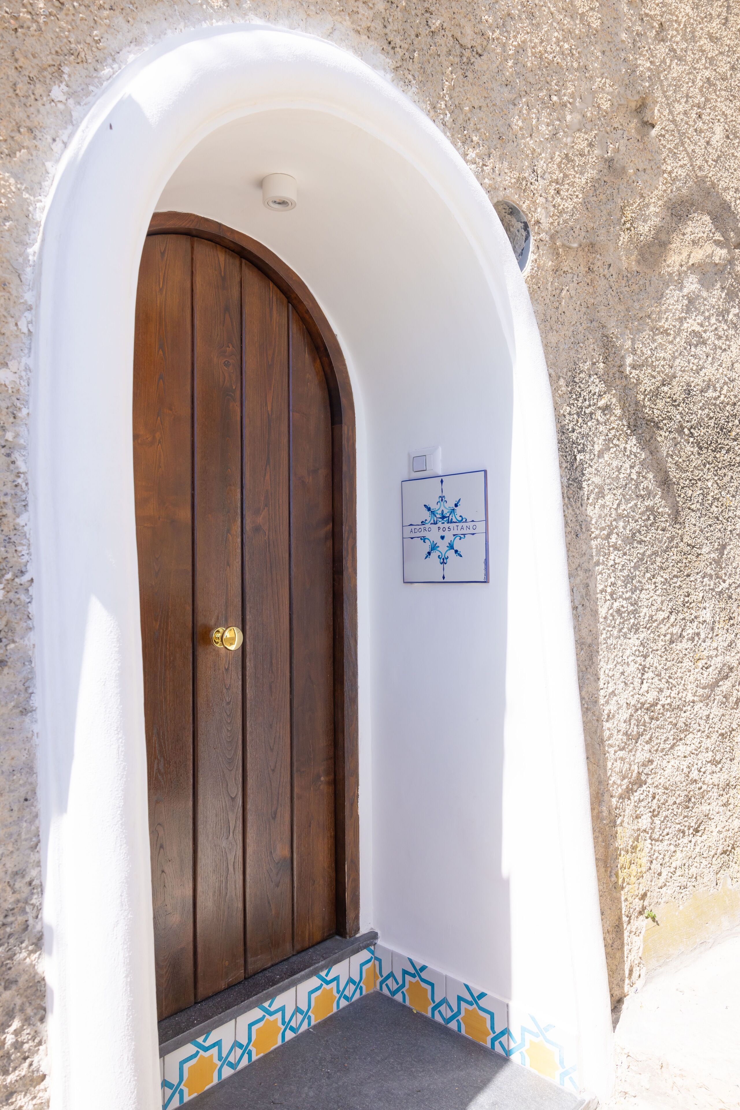 A white-walled building with a wooden door and a small sign on the wall.