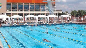 A swimming pool with multiple lanes, white canopies, and a lifeguard tower.