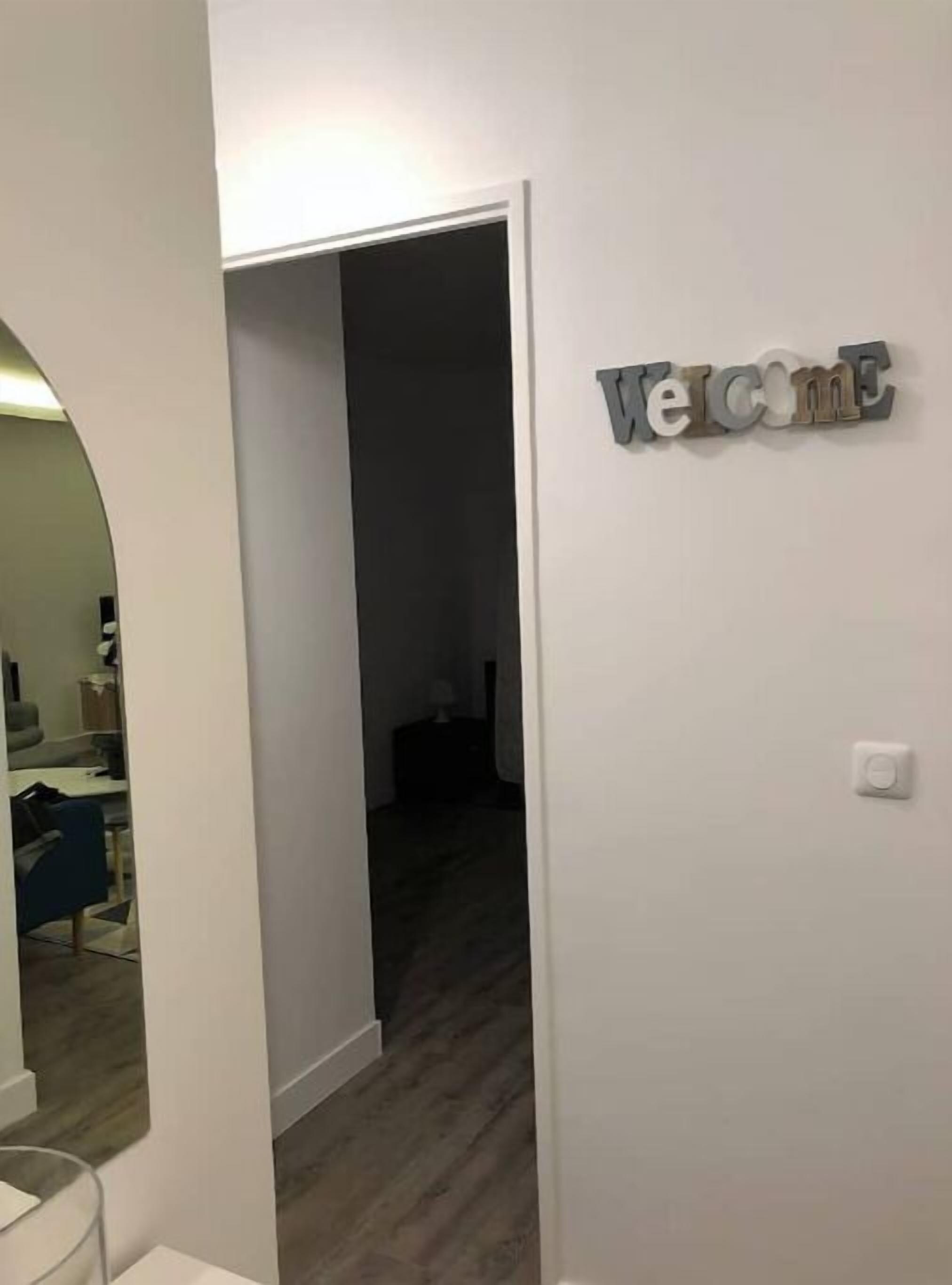 A hallway with a 'Welcome' sign, a mirror, and a door leading to another room.