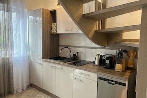 A modern kitchen with white cabinets, a stainless steel sink, and a dishwasher.