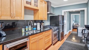 A modern kitchen with wooden cabinets, stainless steel appliances, and a granite countertop.