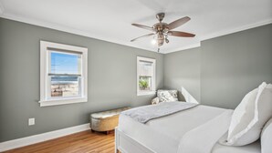 A bedroom with a bed, a ceiling fan, a window, and a bench.