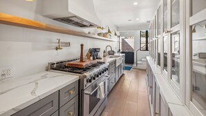 A modern kitchen with a central island, built-in appliances, and a view to the outside.