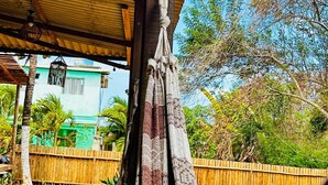 A hammock under a wooden structure with a view of a bamboo fence and greenery. - Pousada Shalon Adonai Noronha (Fernando de Noronha)