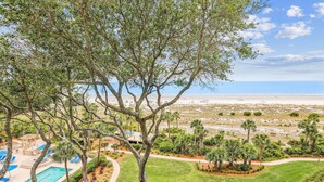 A resort with a pool area, palm trees, and a view of the beach.
