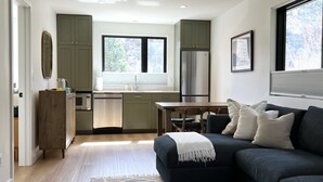 A modern living room with a dark sofa, a coffee table, and a patterned rug. - Tranquility Base, Modern One-Bedroom Apartment (Carbondale)